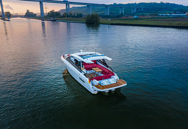 The BAVARIA VIDA 33 on a large calm river with the shore and sunset in the background.