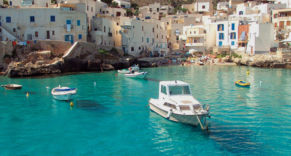 Two boats in a turquoise blue bay of a small Mediterranean town.