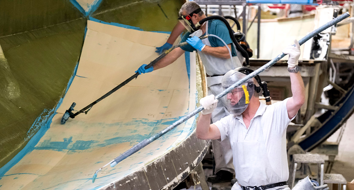 Two men with protective masks and long laminating tools and blue paint.