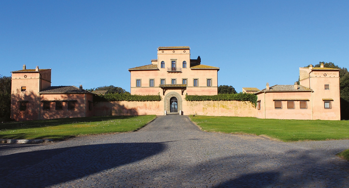A luxurious large property with a light-coloured wall and two towers.
